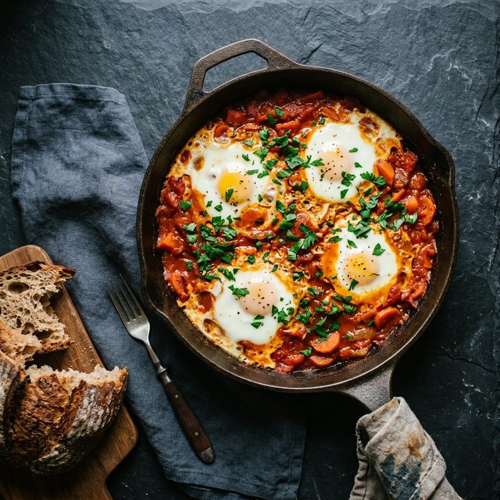 Eggs baked in tomato sauce in a cast iron pan with torn bread